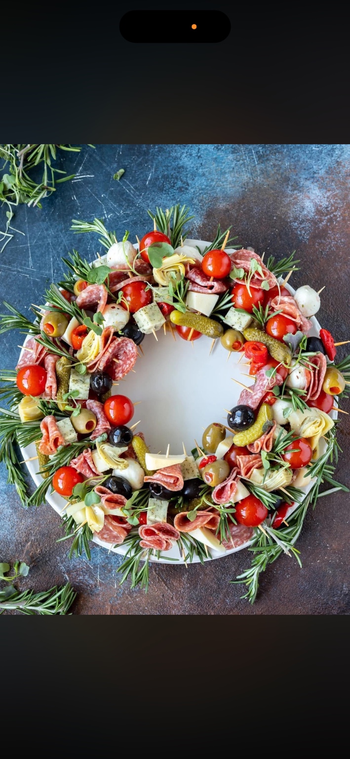 A wreath of savory skewers with olives, tomatoes, and rosemary.